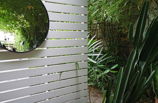 made of white wooden panels ,circular mirror and cactus plant pots