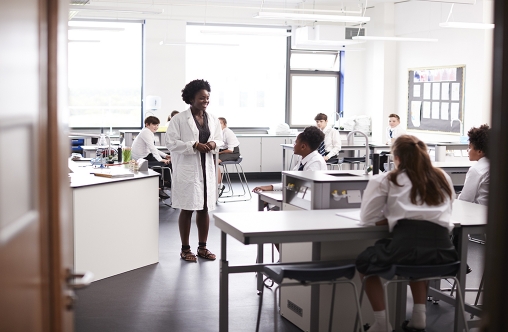 Female High School Tutor Teaching High School Students Wearing Uniforms In Science Class